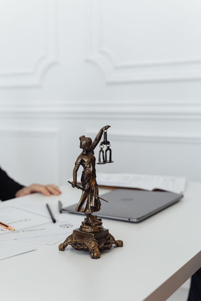 Services Close-up of Lady Justice statue on a white table in an office setting.