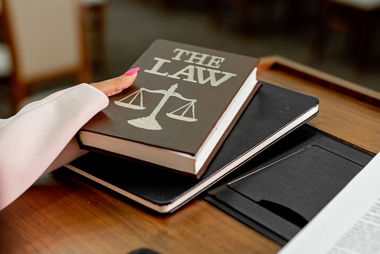 Services Closeup image of a law book titled 'The Law' on a wooden desk with scales of justice.